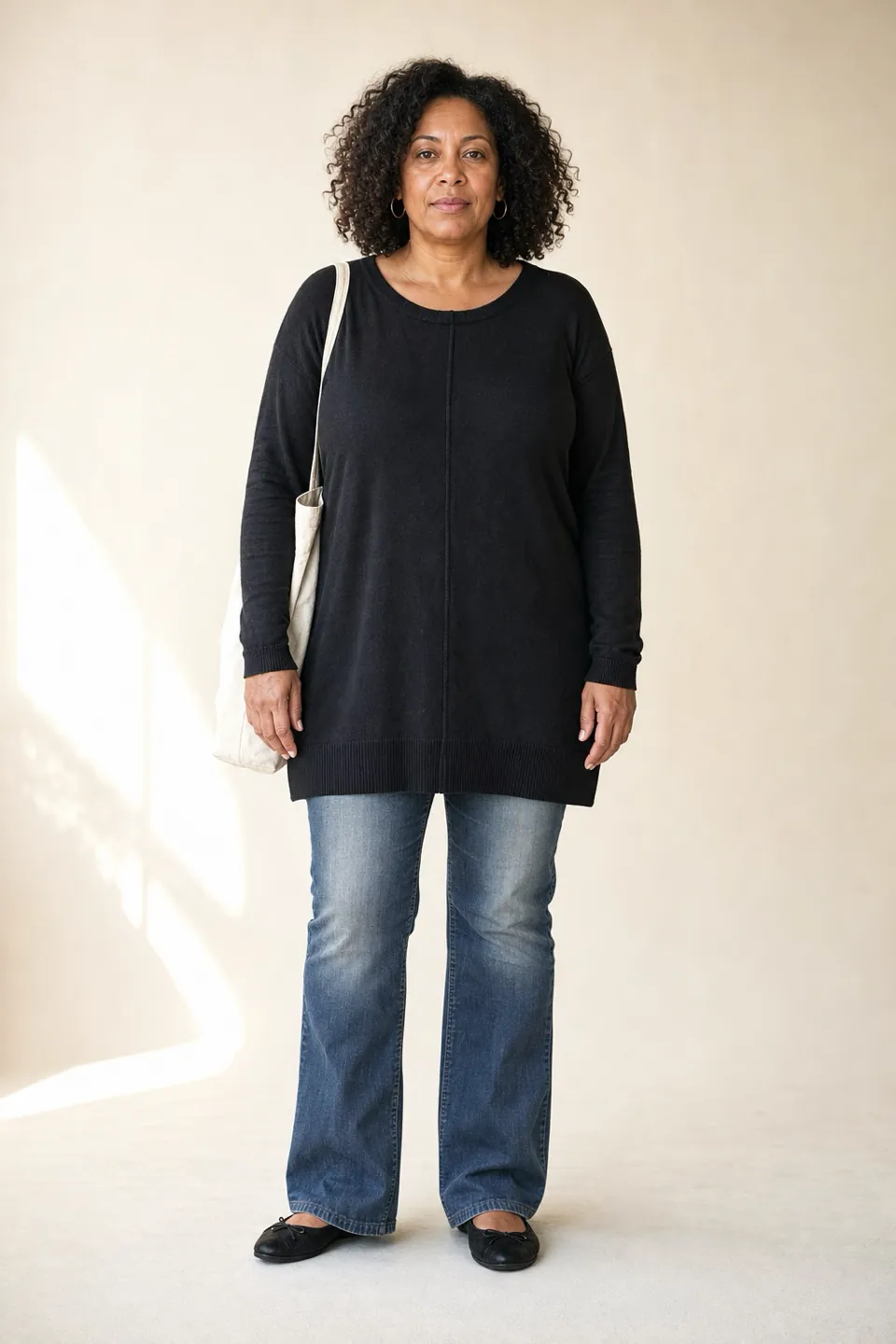 A woman in her late forties in a long loose black tunic, boot-cut jeans and flat black shoes